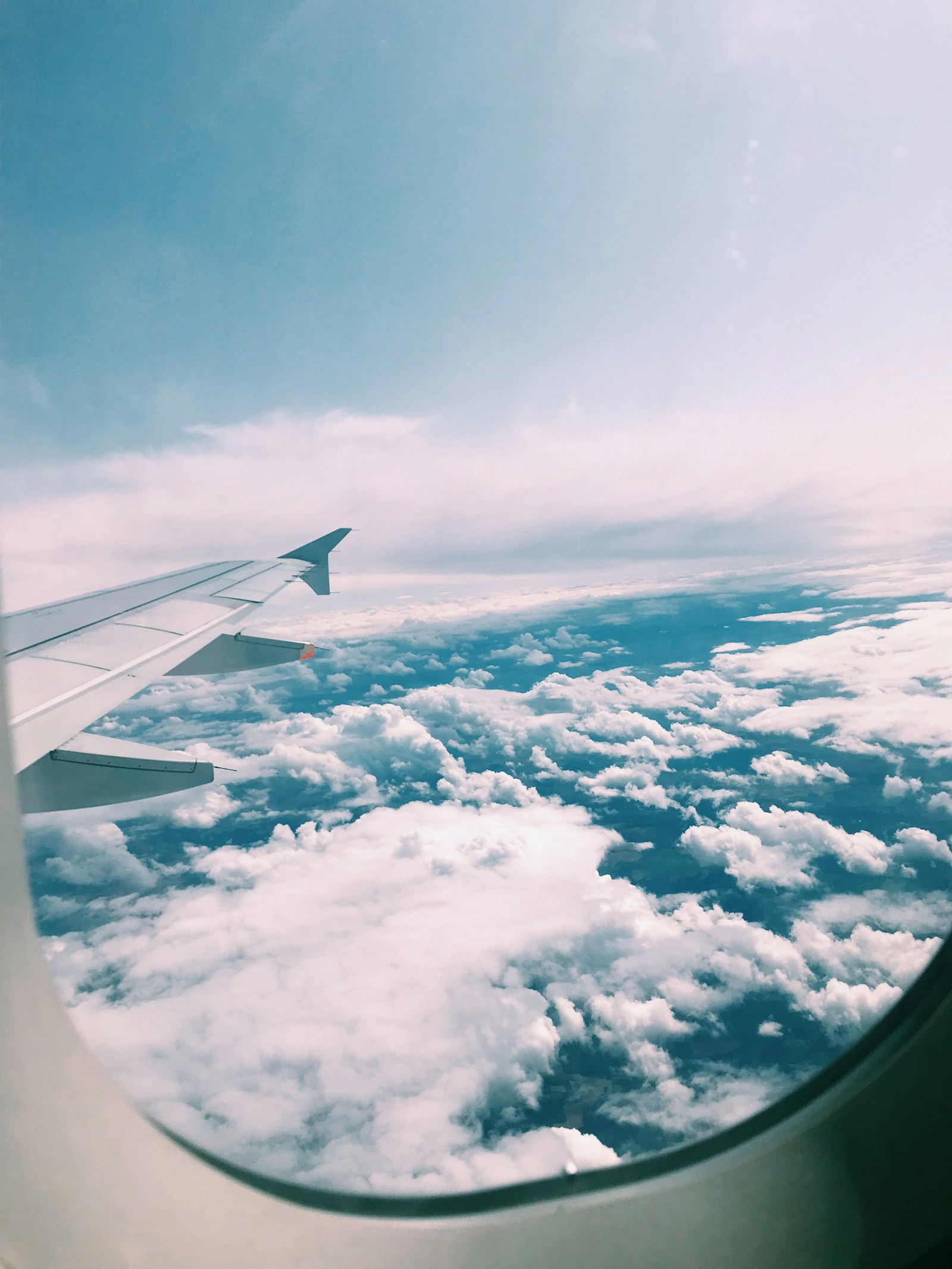 Aircraft wing flying above bright clouds